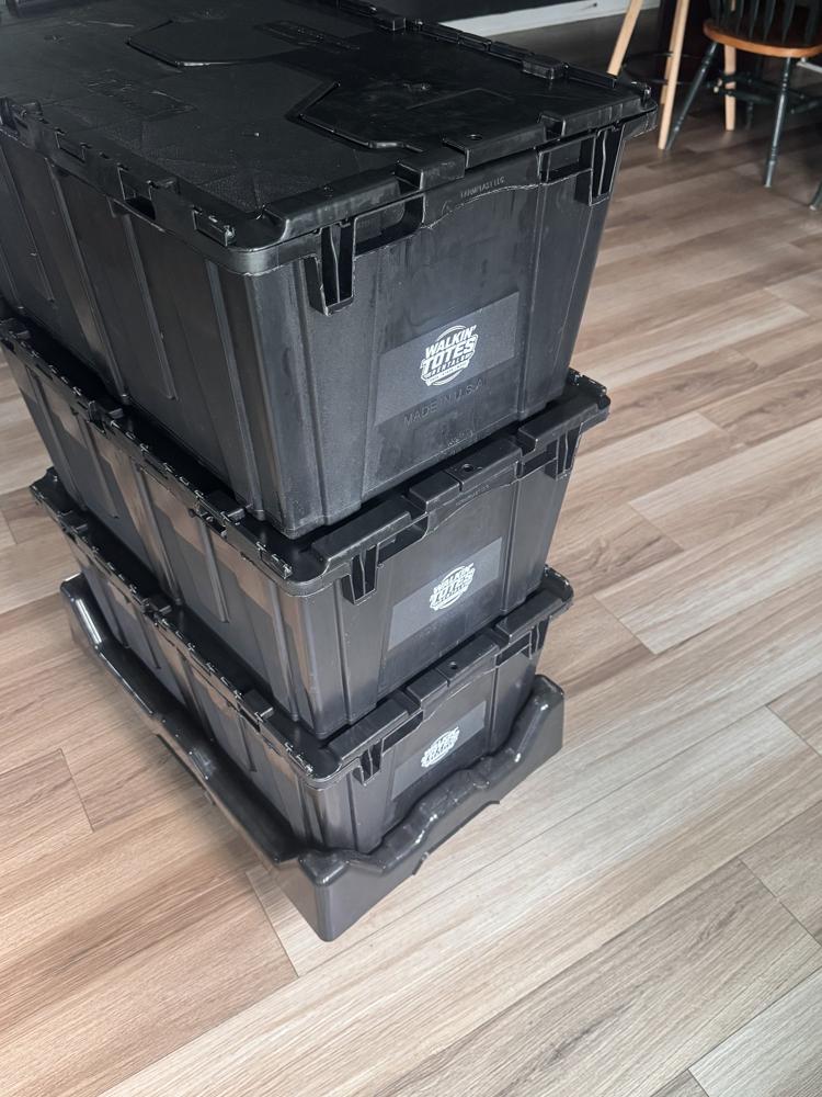 Three black attached-lid Walkin' Totes stacked on a black four-wheel dolly